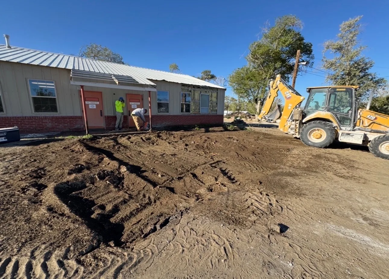 Backhoe and crew working on a commercial building exterior improvement project