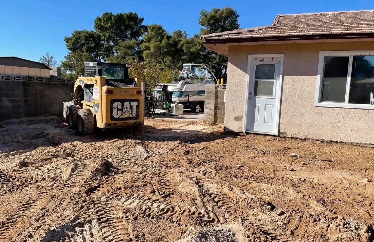 CAT skid steer clearing and leveling a backyard beside a Las Vegas home