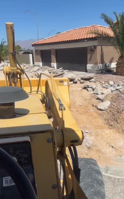 Backhoe removing a concrete driveway during a demolition job